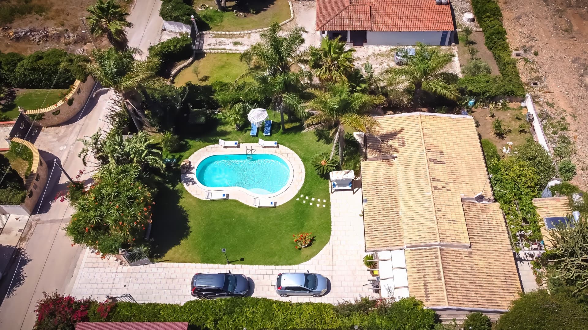 Veduta aerea della villa con piscina e giardino di palme