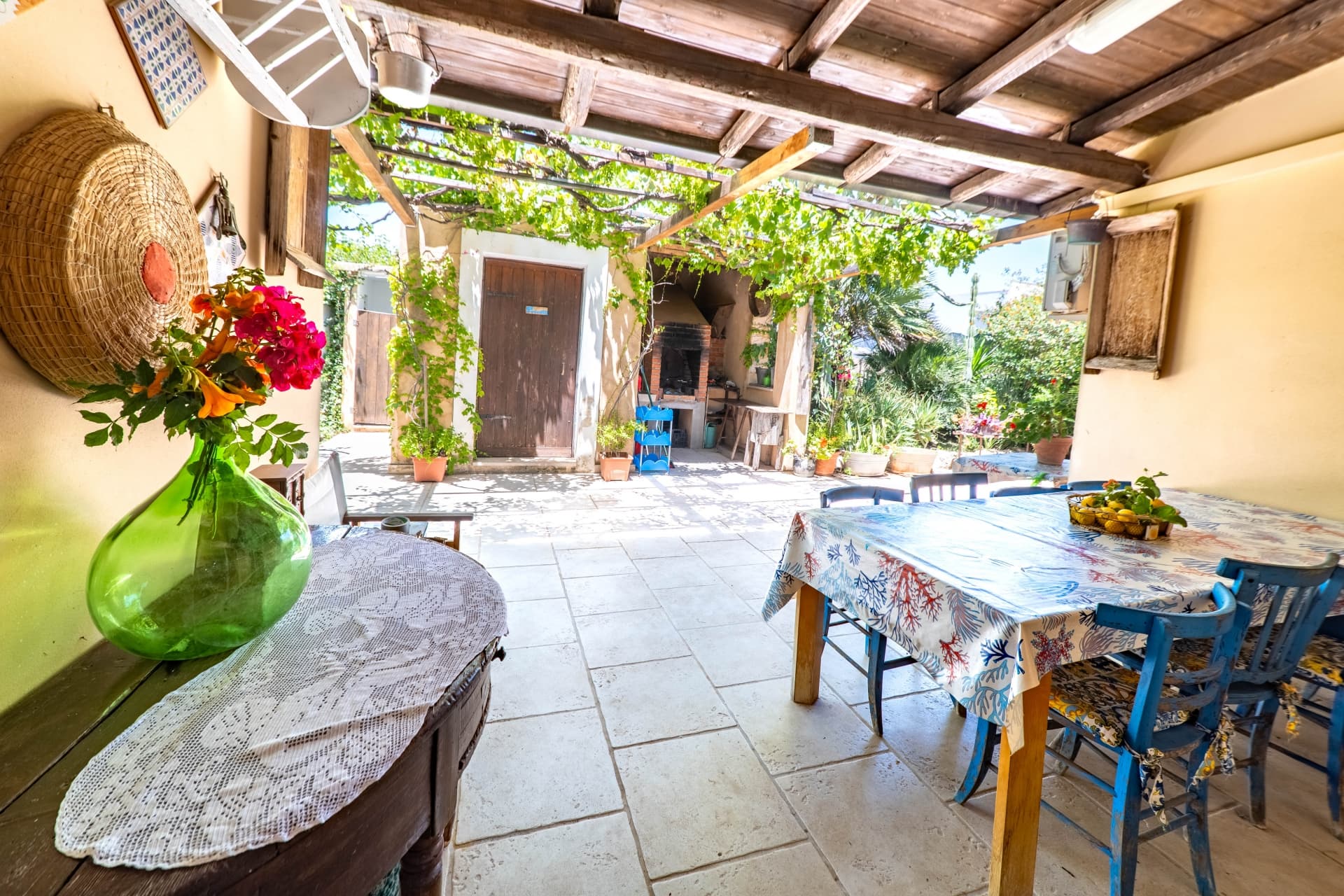 Veranda pranzo con pergolato di vite e barbecue in muratura
